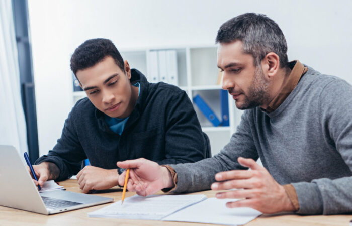 concentrated male coworkers working with papers and laptop in office